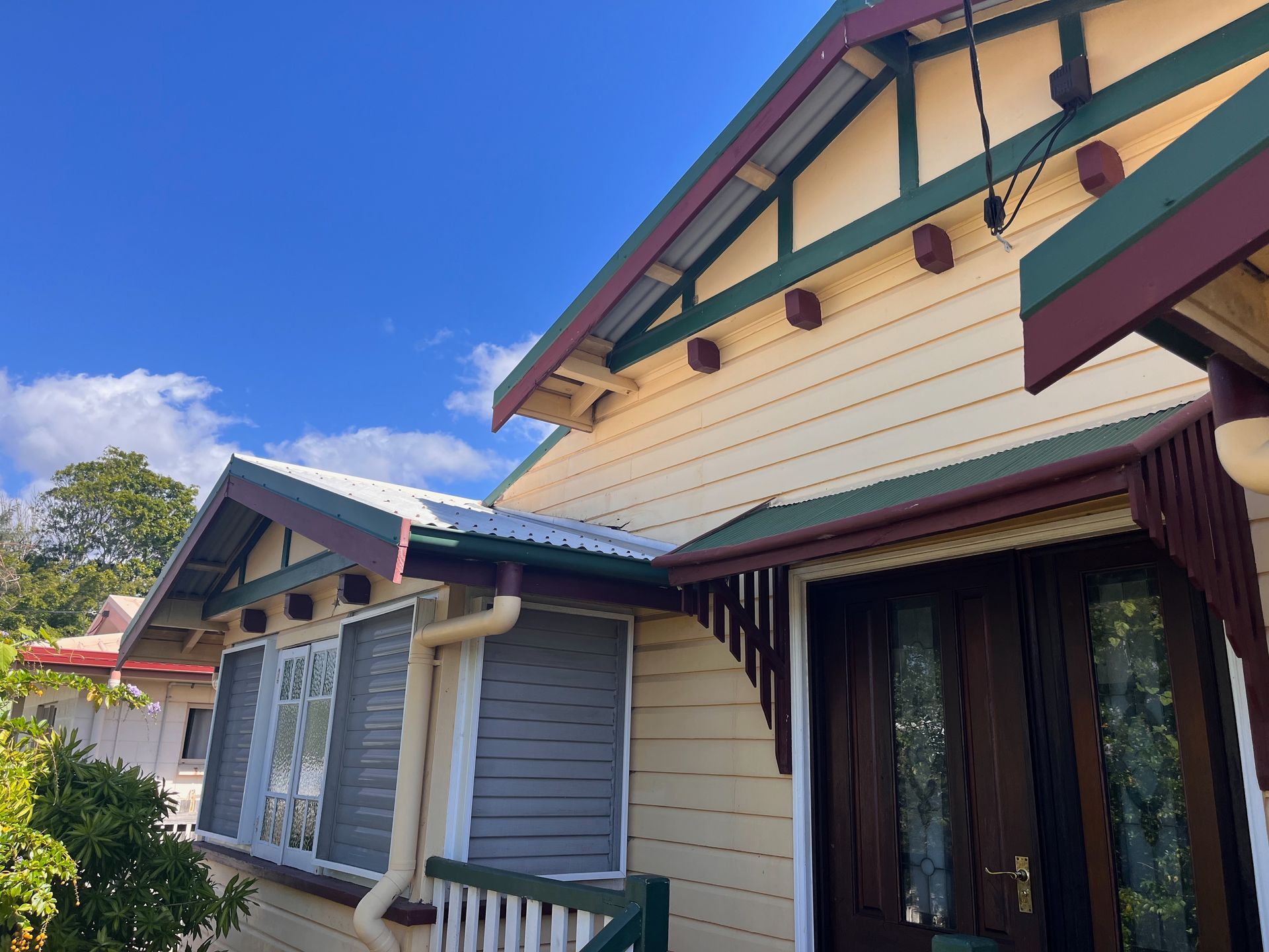 Colorful House Exterior with Cream Siding, Teal Trim, and Maroon Roof — SS Building Services in Townsville, QLD