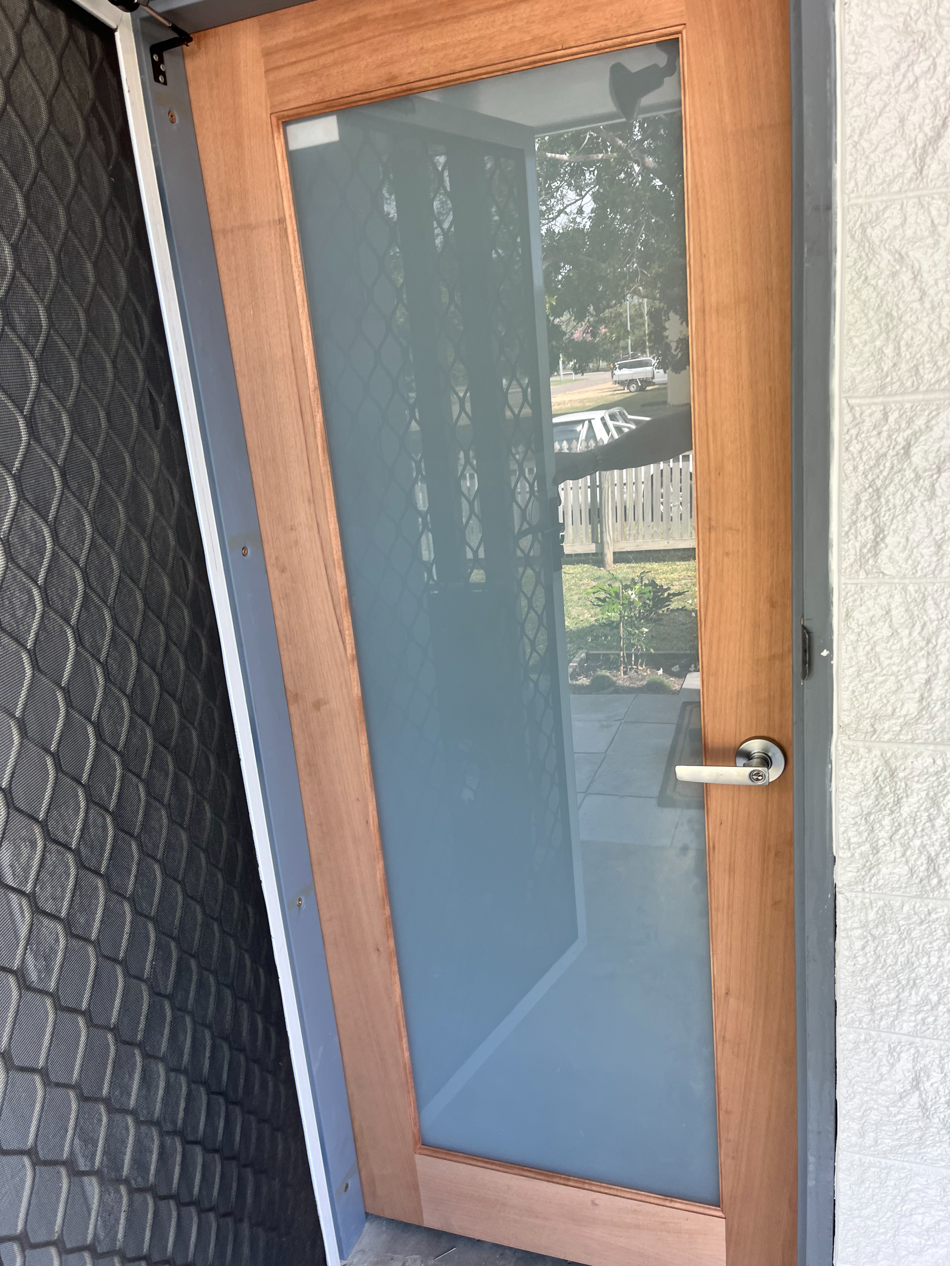 Wood Framed Glass Door with A Silver Handle in A Narrow Outdoor Entryway — SS Building Services in Townsville, QLD