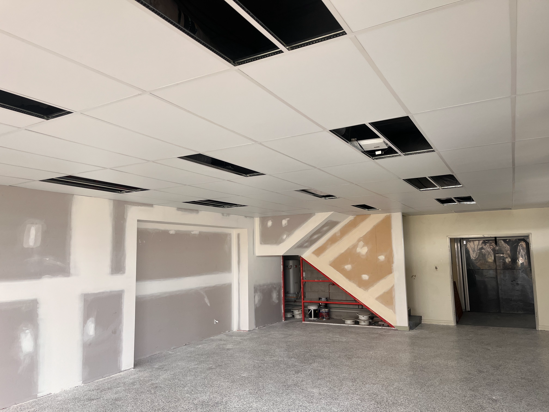 Empty Unfinished Room with Drywall, Drop Ceiling, Staircase, and Open Doorway — SS Building Services in Townsville, QLD