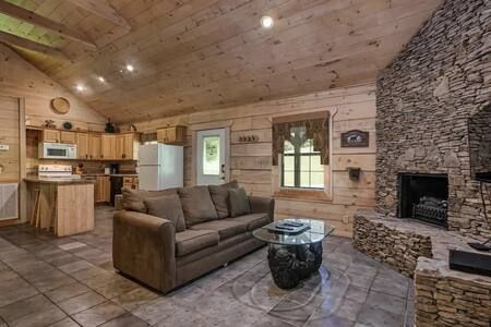 Cozy rustic living room with stone fireplace, brown sofa, and wood-paneled ceiling