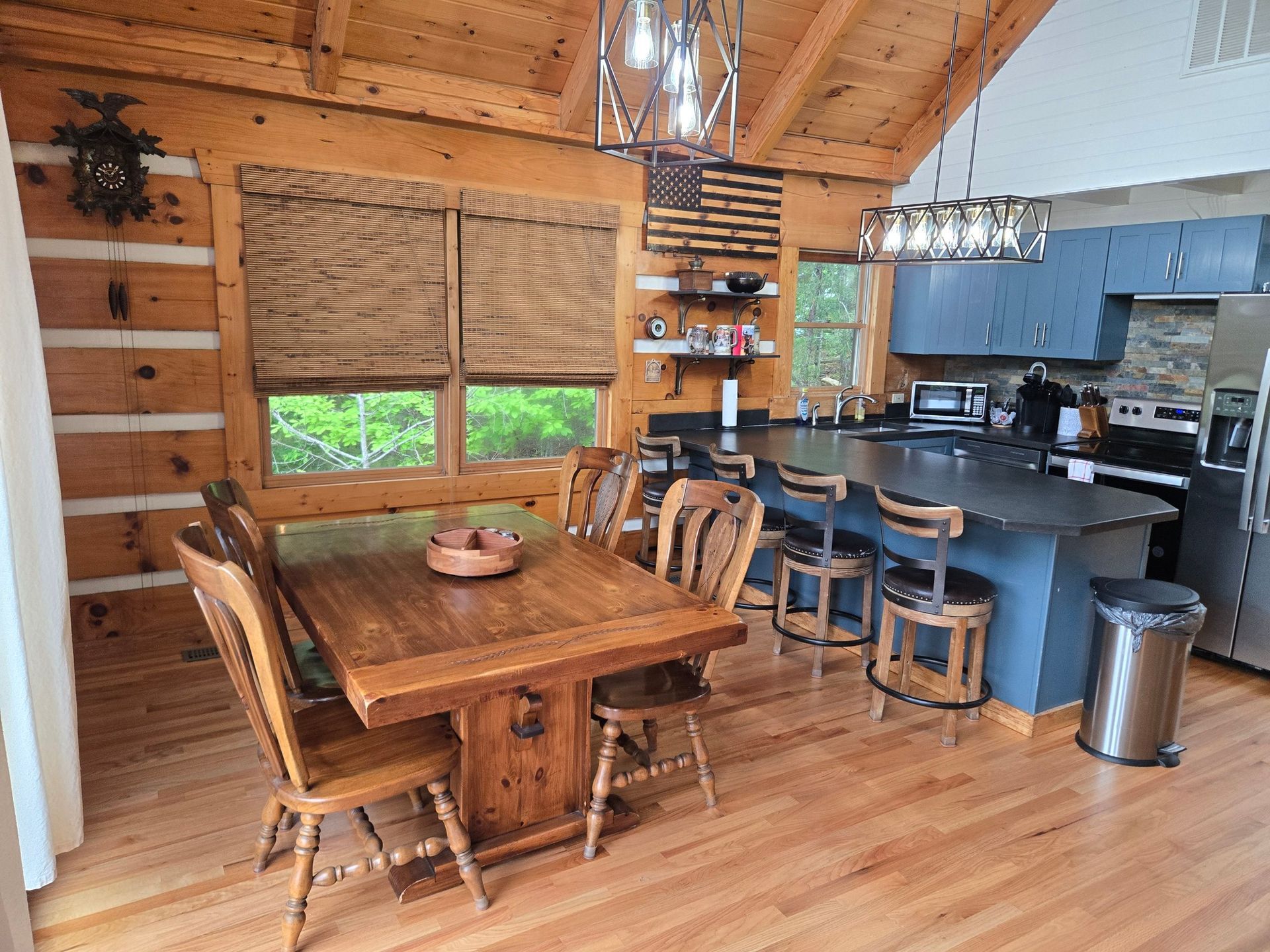Cozy wood cabin dining area with rustic table, chairs, and open kitchen with bar stools