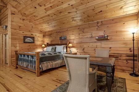 Cozy wooden cabin bedroom with a bed, desk, chair, lamp, and wood-paneled walls