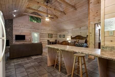 Rustic open-plan kitchen and living area with wood-paneled walls, tiled floor, and island seating