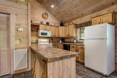 Rustic kitchen with wood cabinets, central island, white refrigerator, and vaulted ceiling