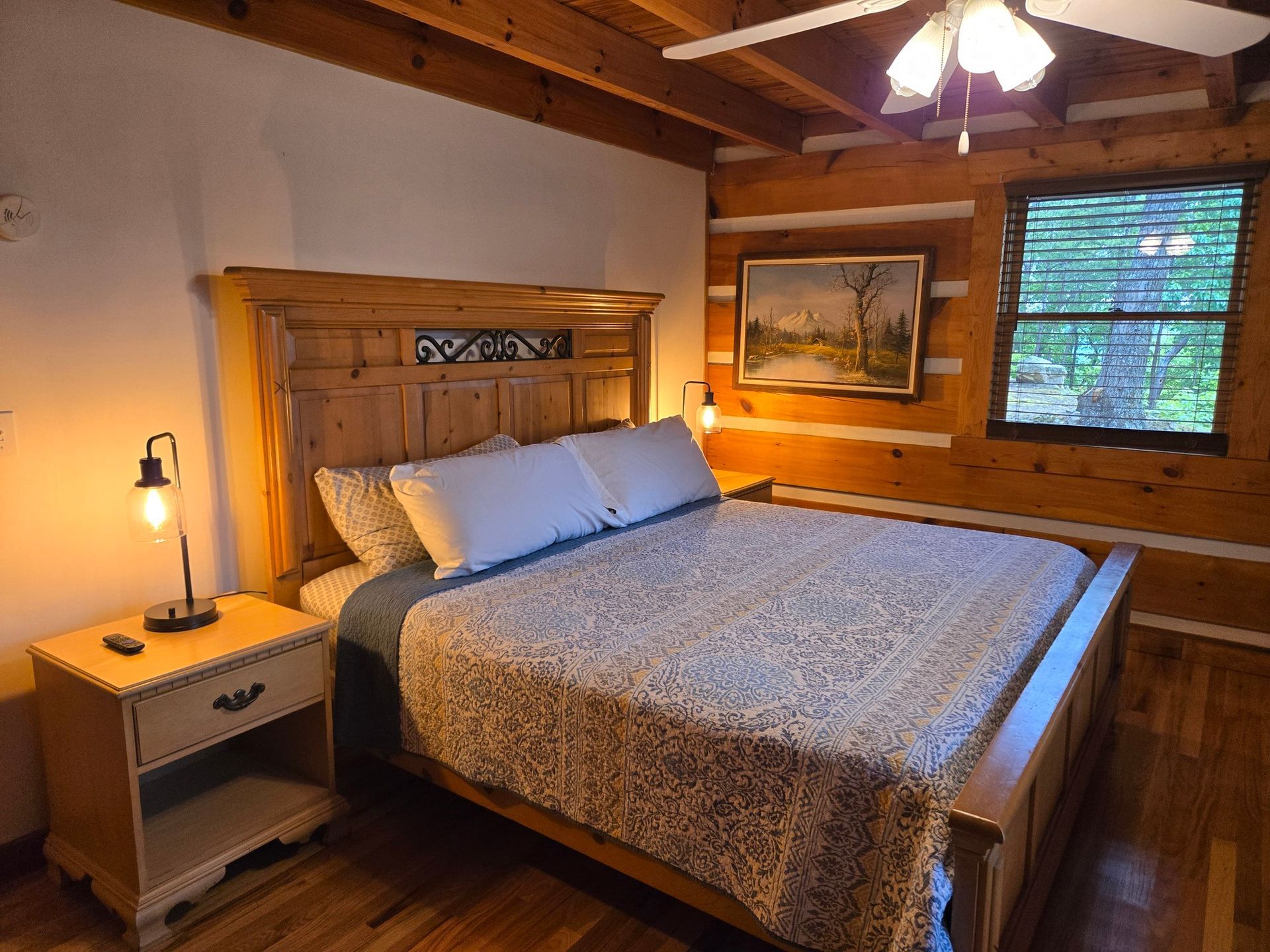 Cozy rustic bedroom with wooden bed, nightstand lamp, and warm cabin walls