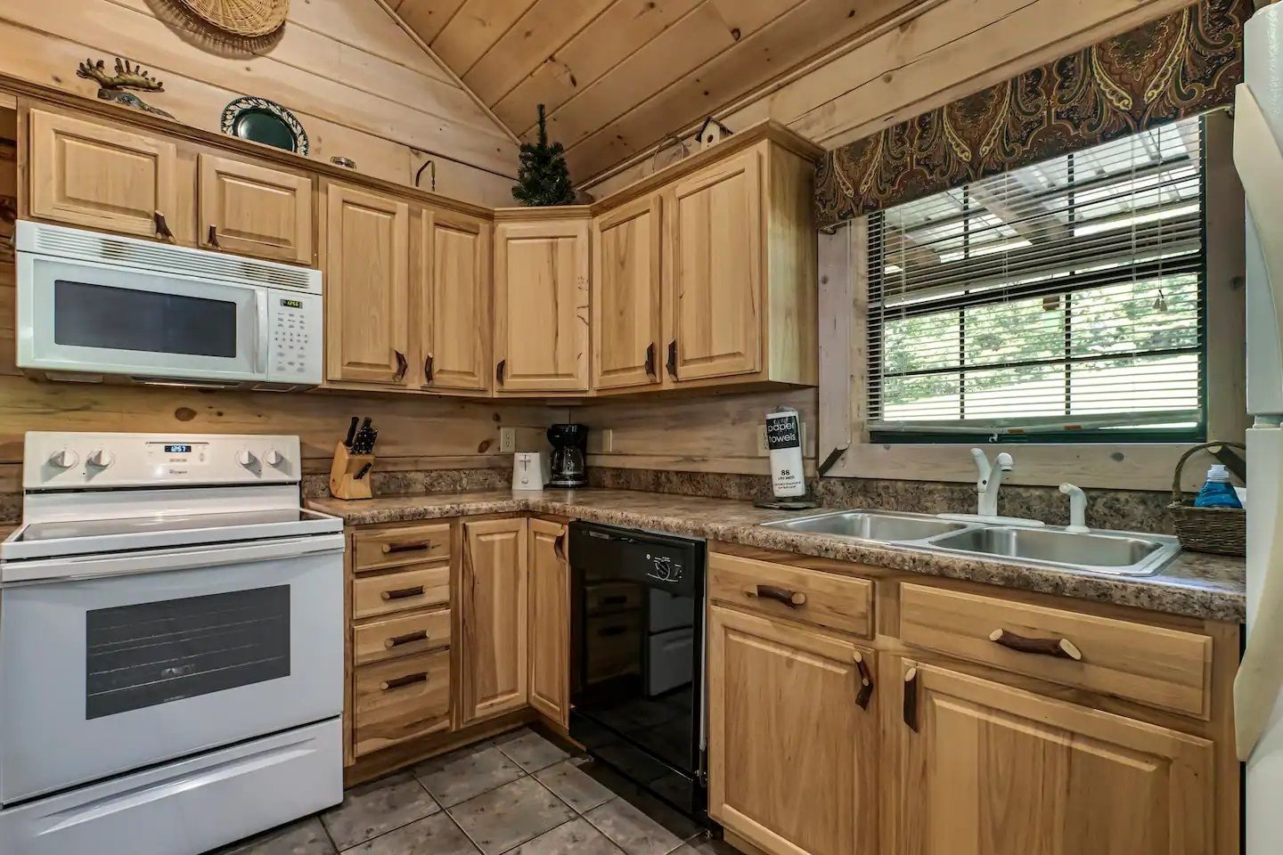 Wooden kitchen with white appliances, granite countertops, and a window over the sink
