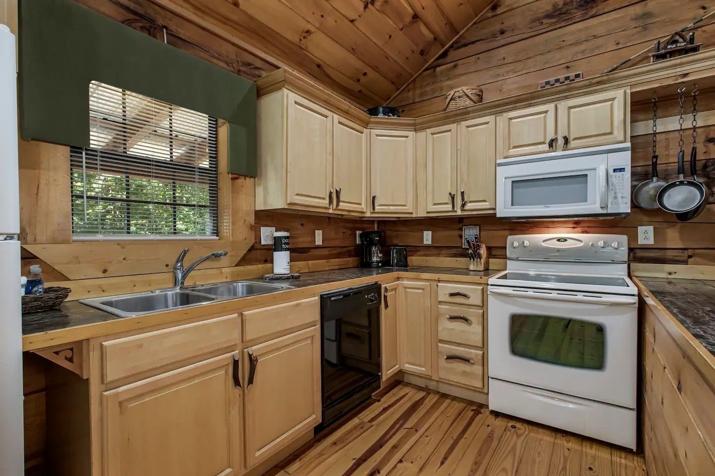 Rustic kitchen with wood cabinets, white appliances, and a vaulted wood ceiling