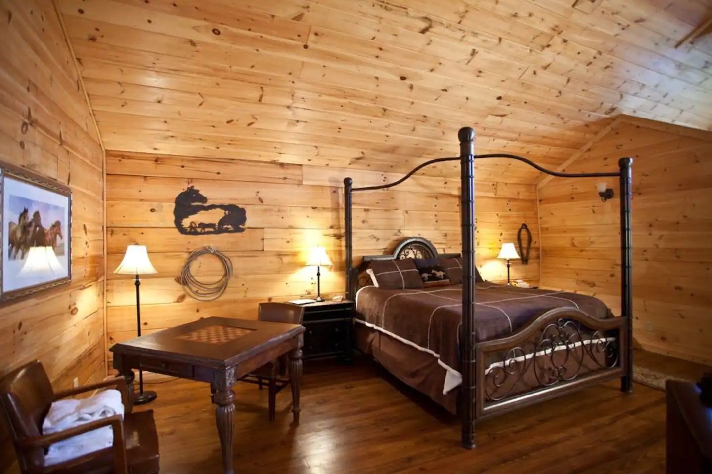 Cozy wooden bedroom with a four-poster bed, bedside lamps, and a small desk and chair