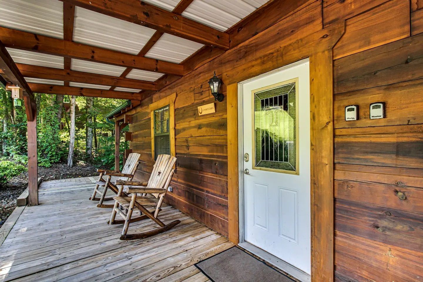 Covered wooden porch with rocking chairs and a white door