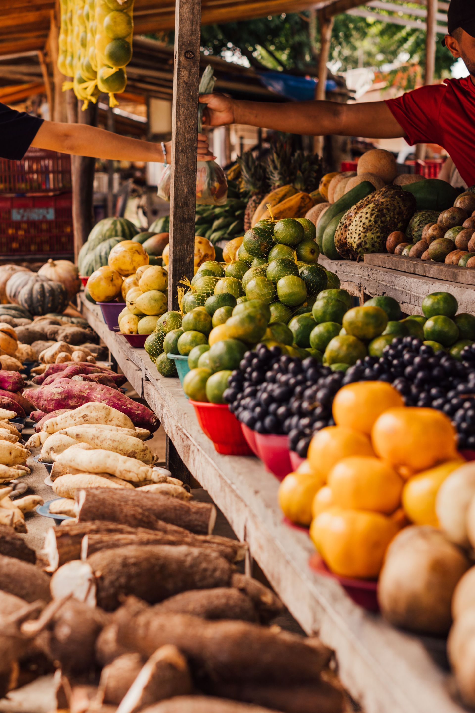 Fruit and root vegetable market stall with colorful produce arranged in wooden baskets and trays