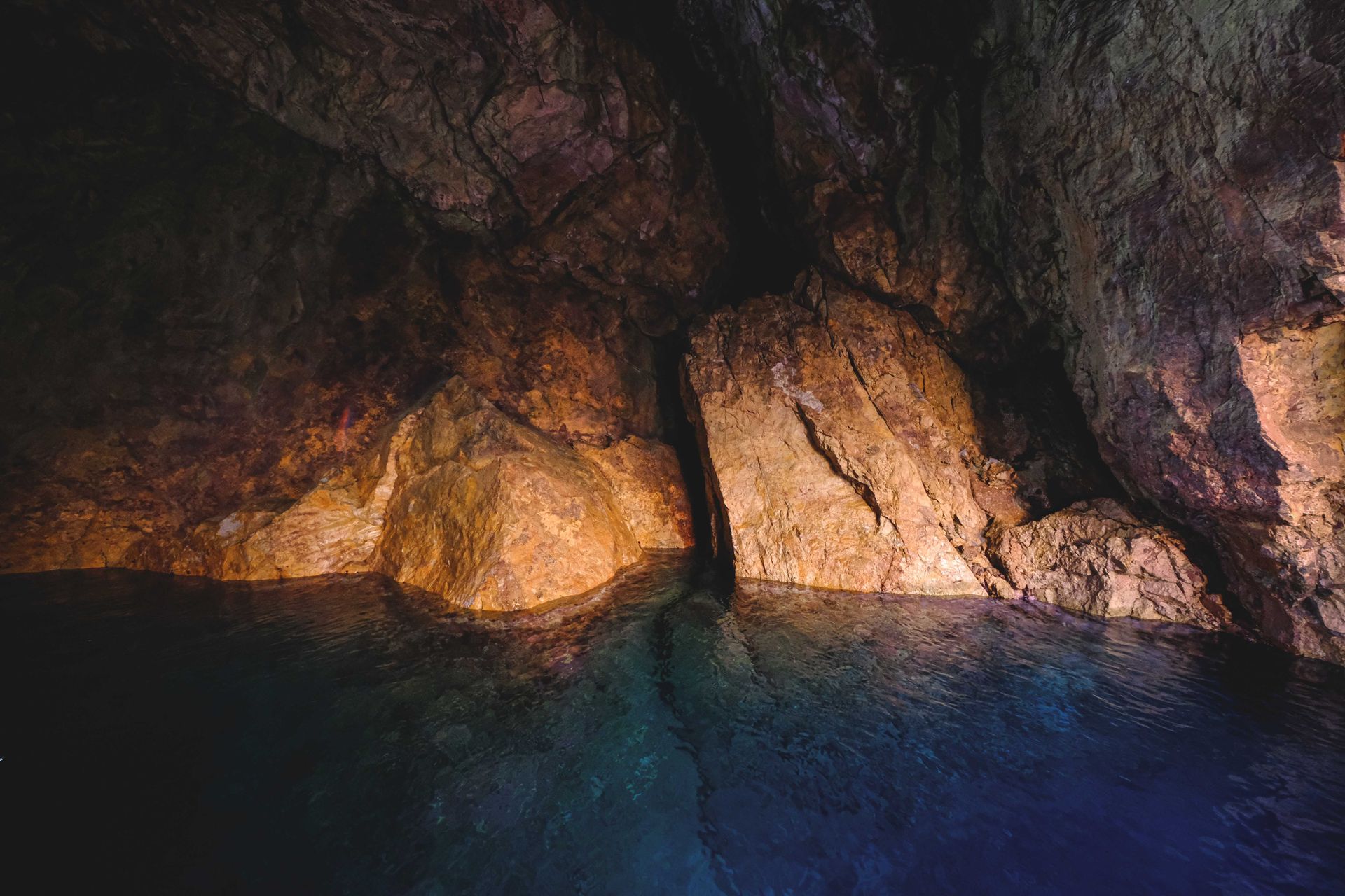 Rocky cave wall glowing in warm light above dark blue water