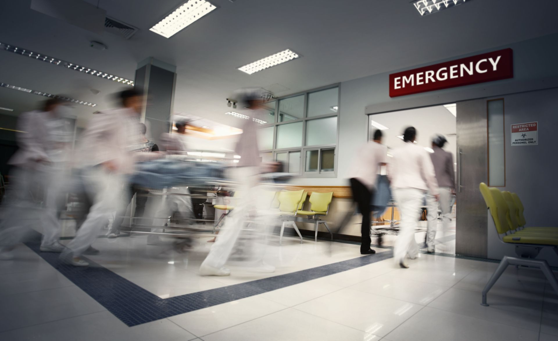 Blurred figures rushing through emergency room doors.