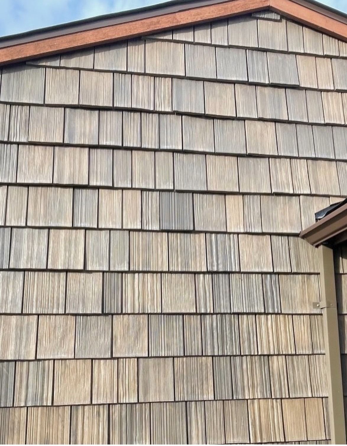 Exterior wall covered in weathered, light brown cedar wood shingles arranged in uniform horizontal rows.