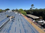 A residential roof under construction with blue CertainTeed underlayment covering the wooden roof deck.