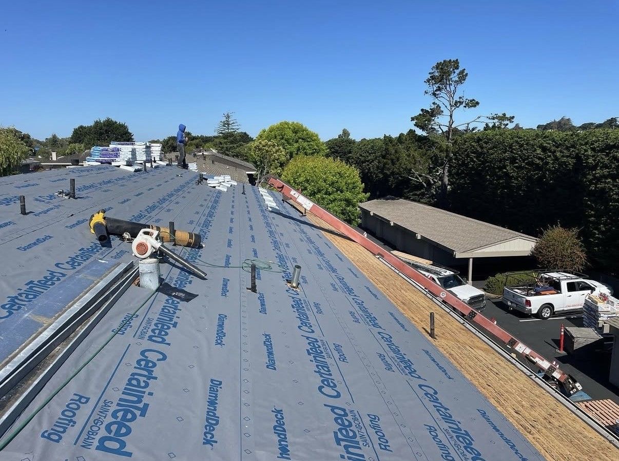 A residential roof under construction with blue CertainTeed underlayment covering the wooden roof deck.