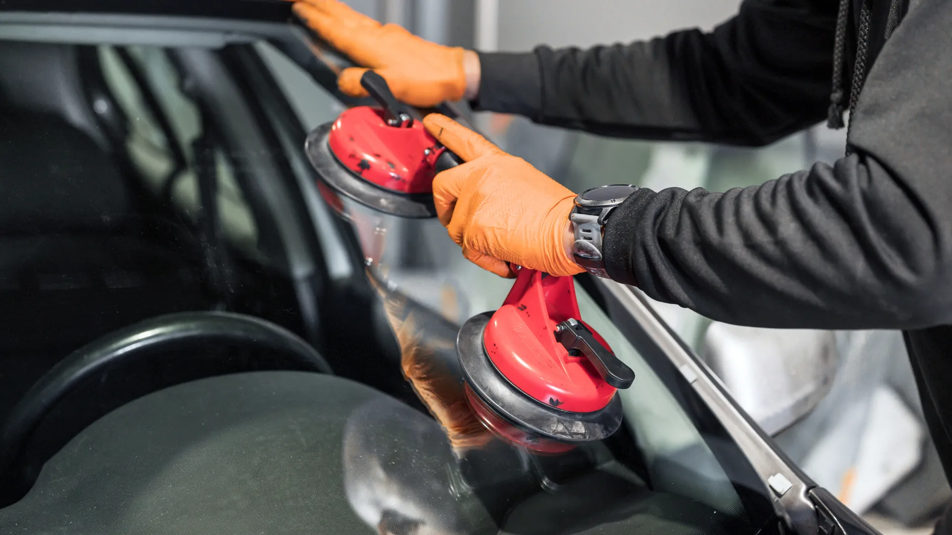 Person using red suction cups to handle car window.
