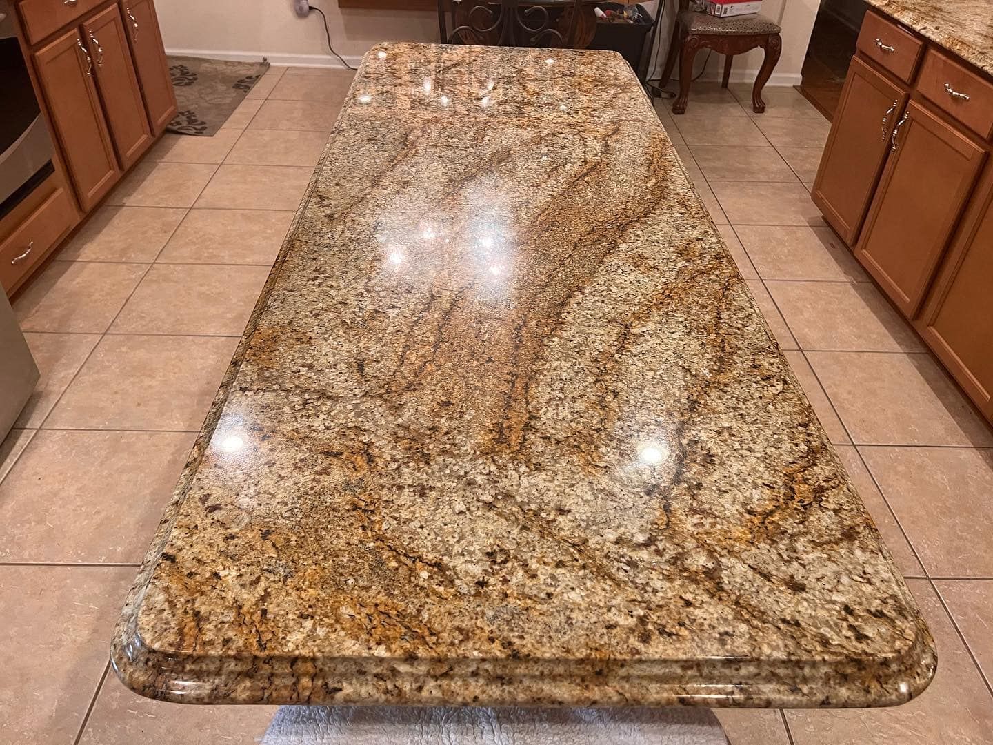 Large polished granite kitchen island countertop with a tan, brown, and cream mottled pattern
