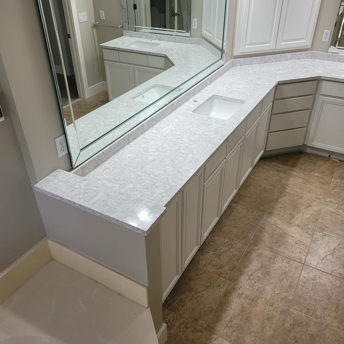 Modern bathroom vanity with white countertop, large mirror, and beige tile floor
