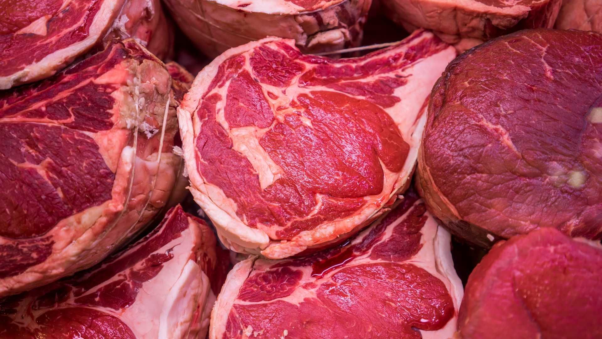 A close up of a pile of raw beef steaks.