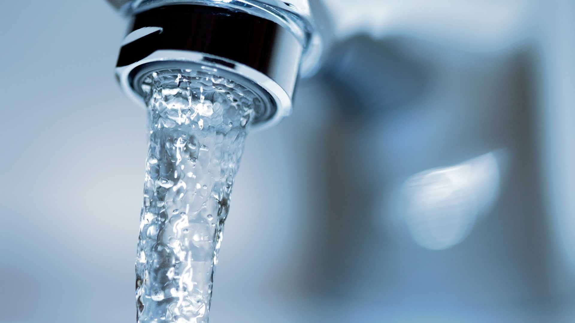 Water is pouring out of a faucet in a bathroom.