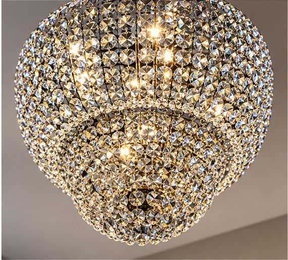 Living contemporaneo con lampadario decorativo sospeso al centro, luce calda e arredi eleganti.