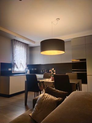 Interno residenziale con faretti incassati, applique e lampadario di design studiati per valorizzare gli arredi.