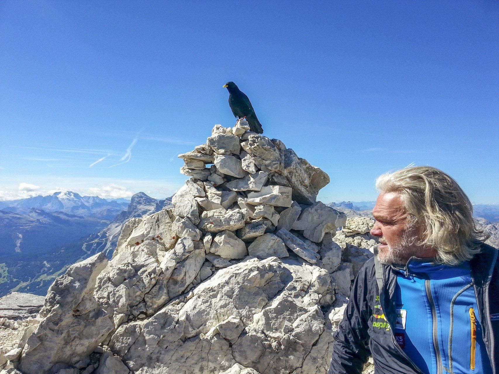 Ein Mann steht auf einem Berggipfel neben einem Steinhaufen.
