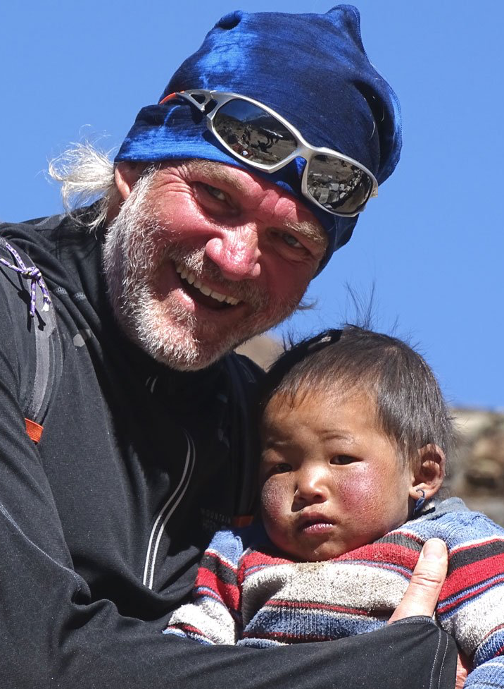 Ein Mann mit Sonnenbrille und blauem Hut hält ein Baby