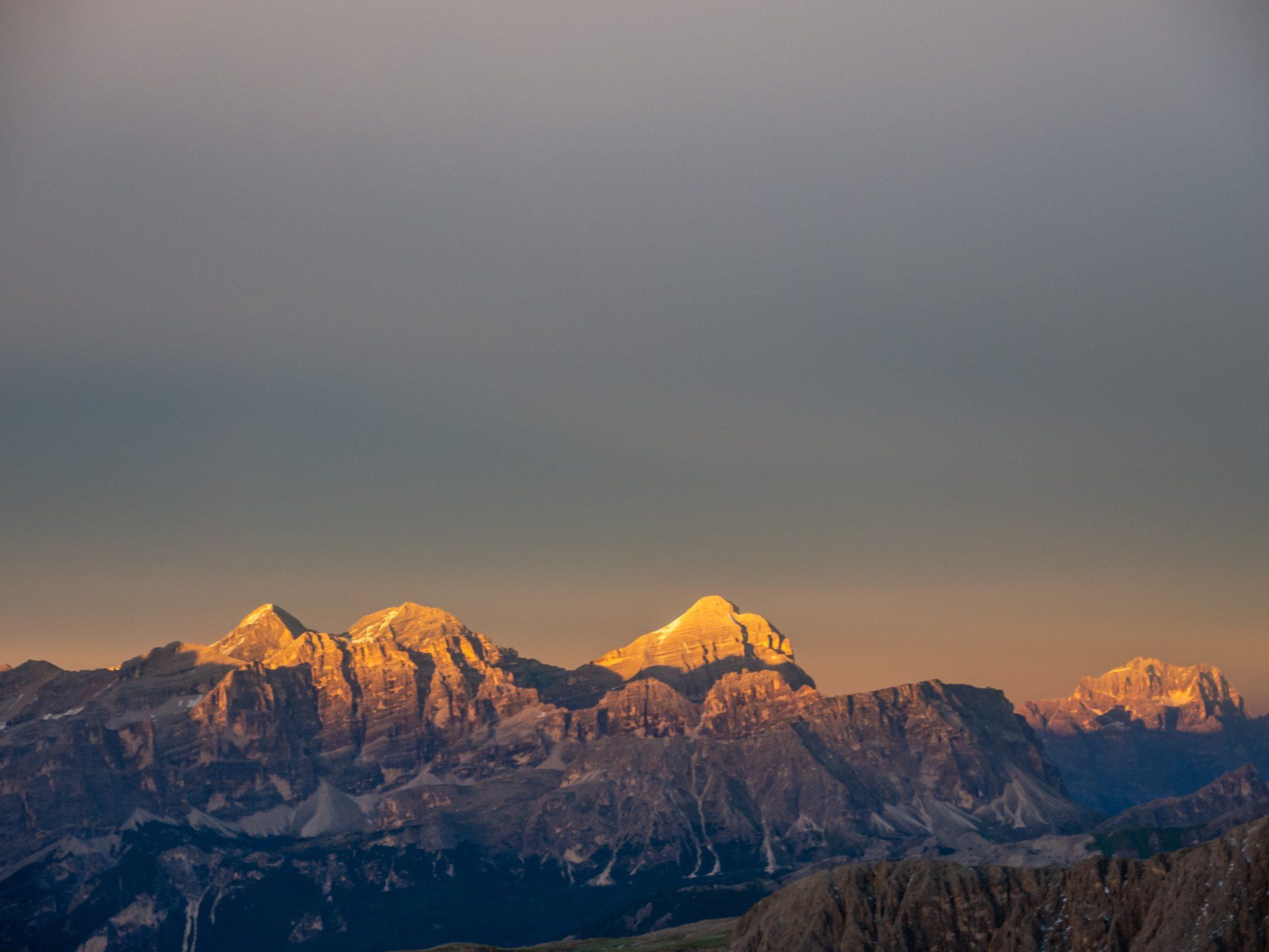 Ein Blick auf eine Bergkette bei Sonnenuntergang mit einem bewölkten Himmel im Hintergrund.