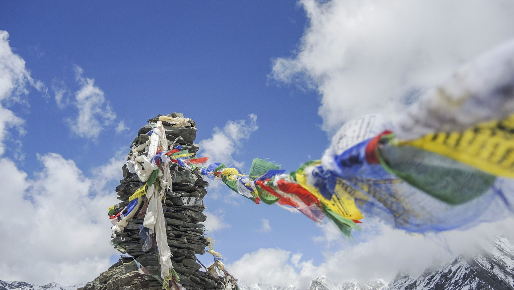 Auf einem Berggipfel wehen viele Flaggen im Wind.