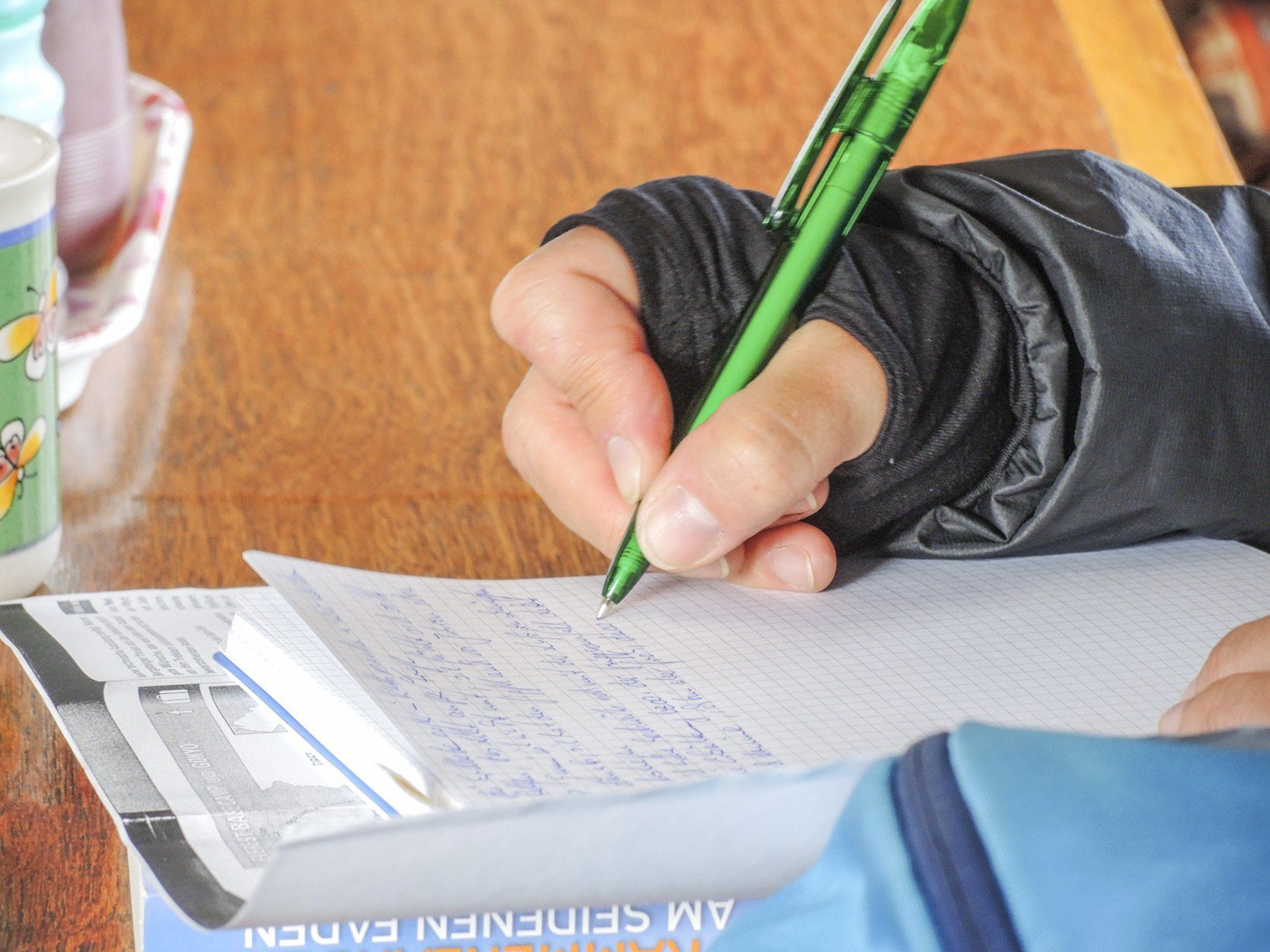 Eine Person schreibt mit einem grünen Stift auf ein Stück Papier