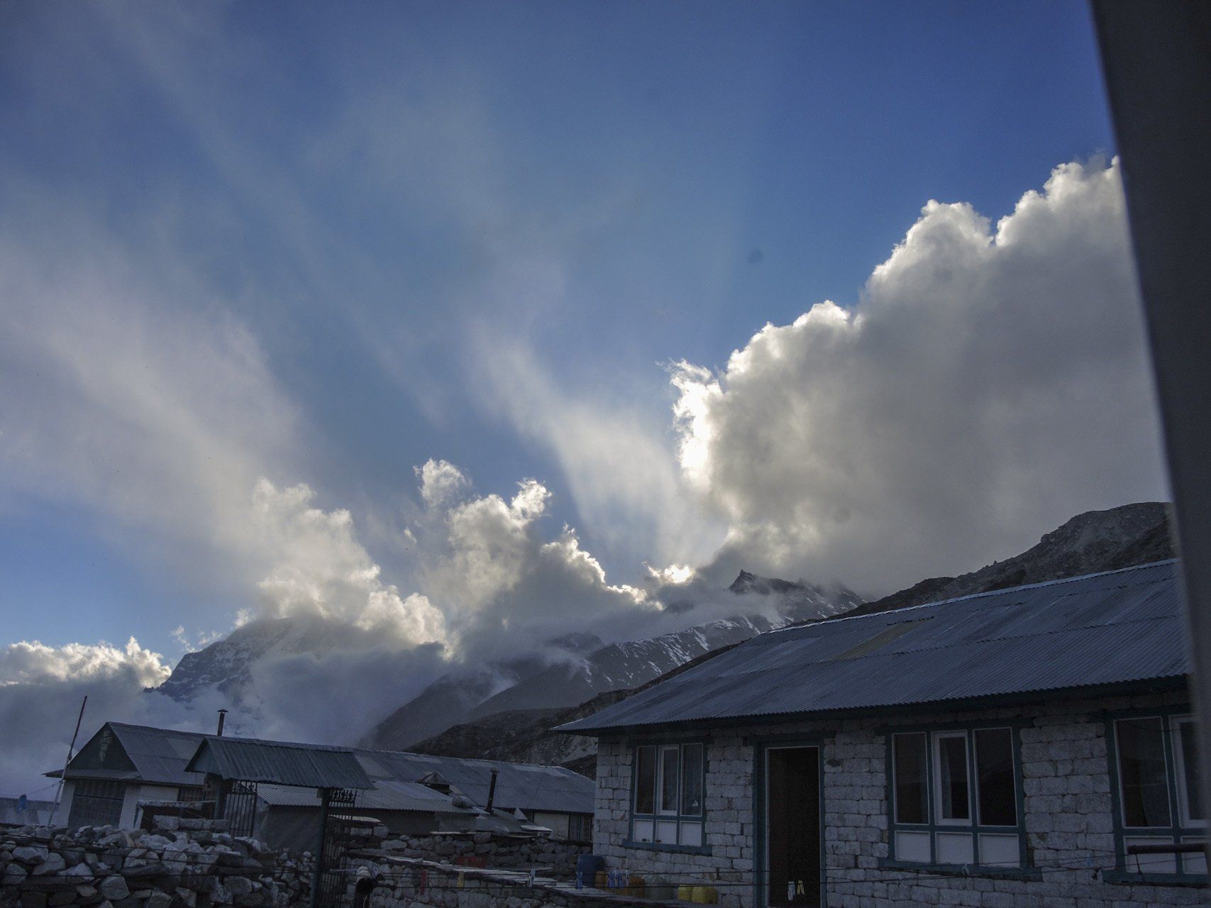 Ein Haus mit einem Berg im Hintergrund und Wolken am Himmel