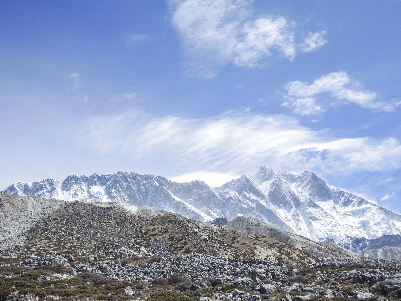 Eine schneebedeckte Bergkette mit blauem Himmel und Wolken im Hintergrund