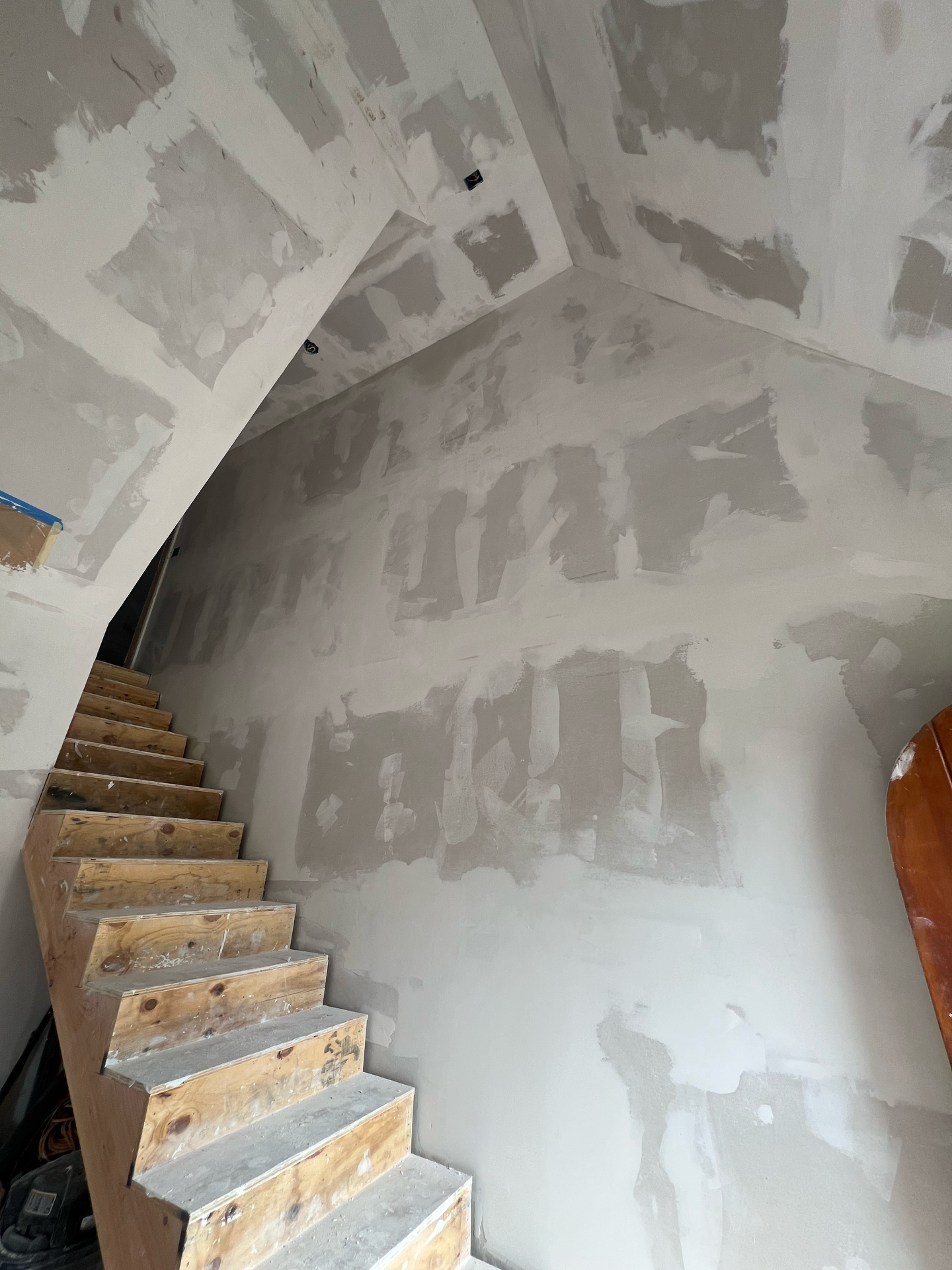 A staircase is being built in a room with a white wall.