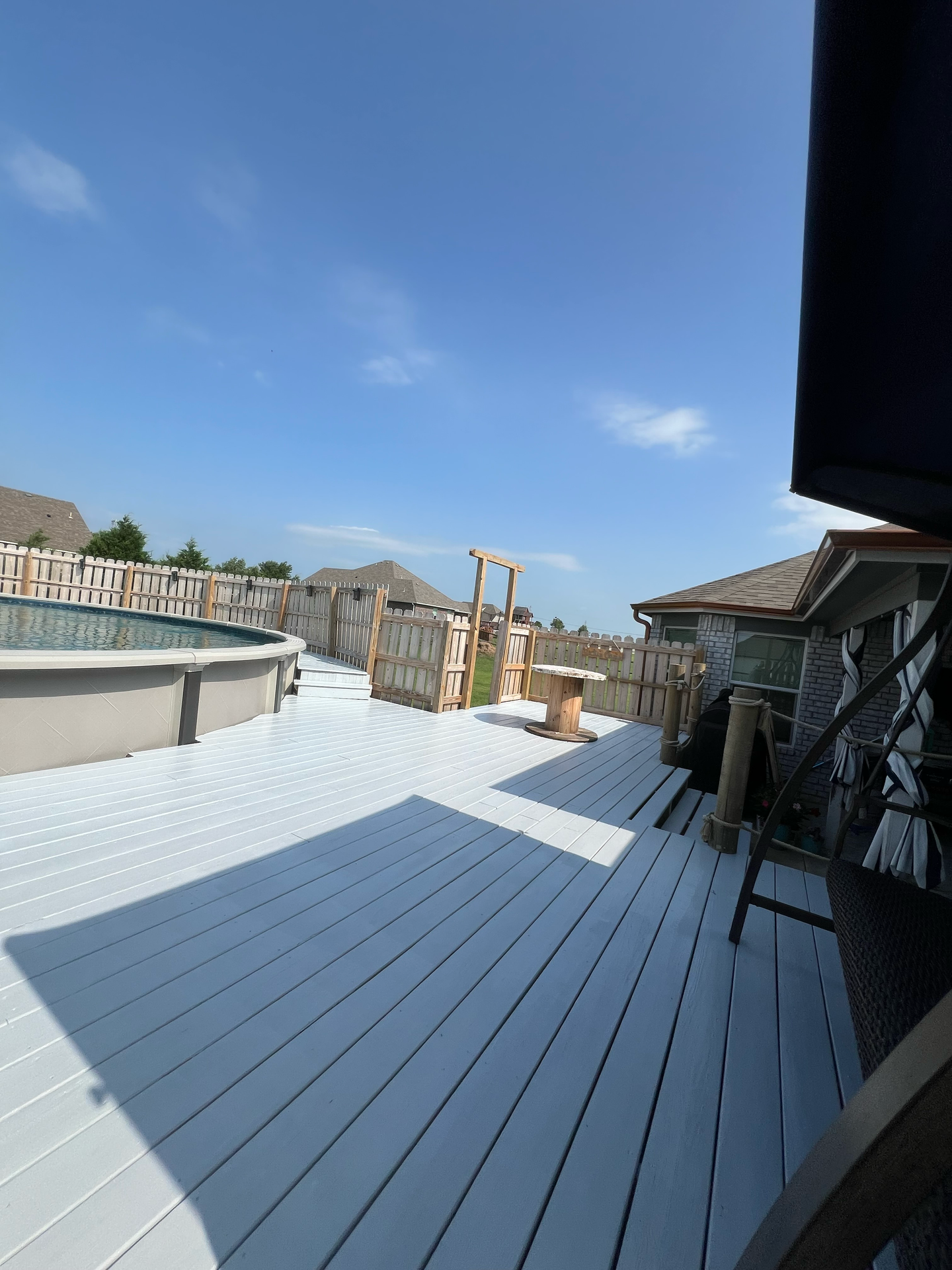 A white deck with a swimming pool in the background