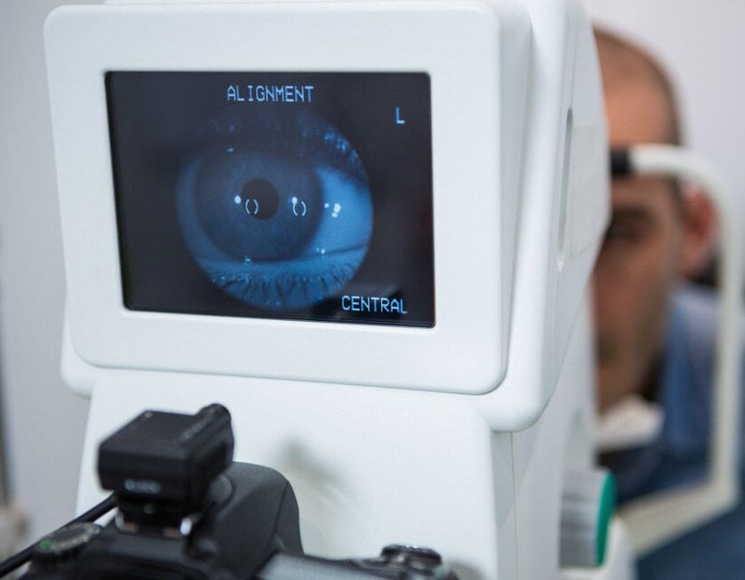 A Man is Getting His Eyes Checked by an Ophthalmologist — Ian Emslie Optometrist In Warners Bay, NSW