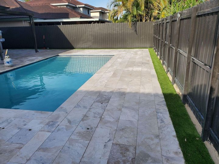 A backyard with a fence and a lush green lawn.