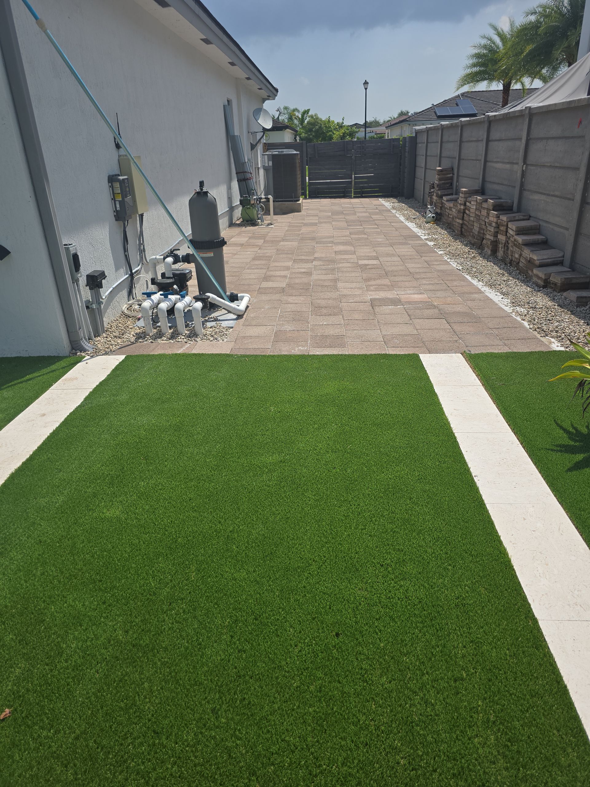 A driveway with a brick walkway and a lawn in front of a house.
