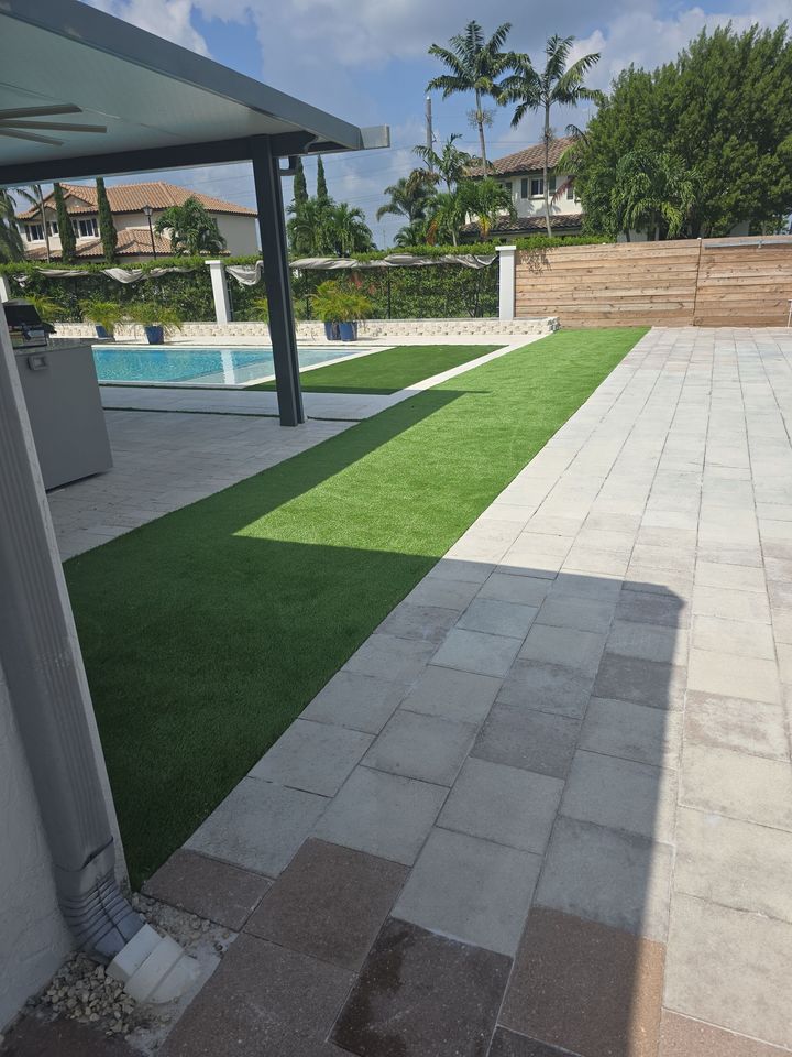A patio with a lawn and a pool in the background