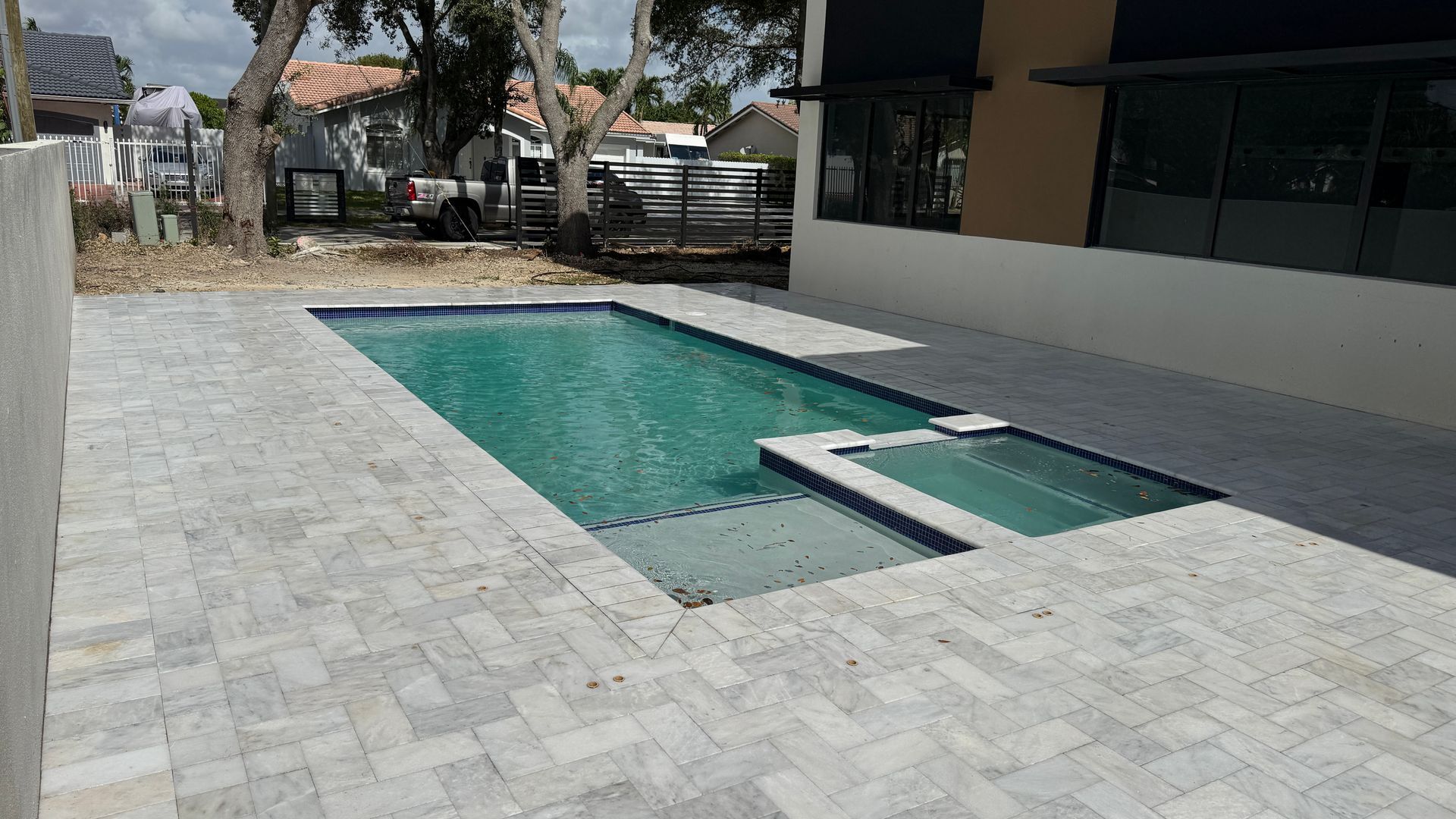 There is a large swimming pool in the backyard of a house.