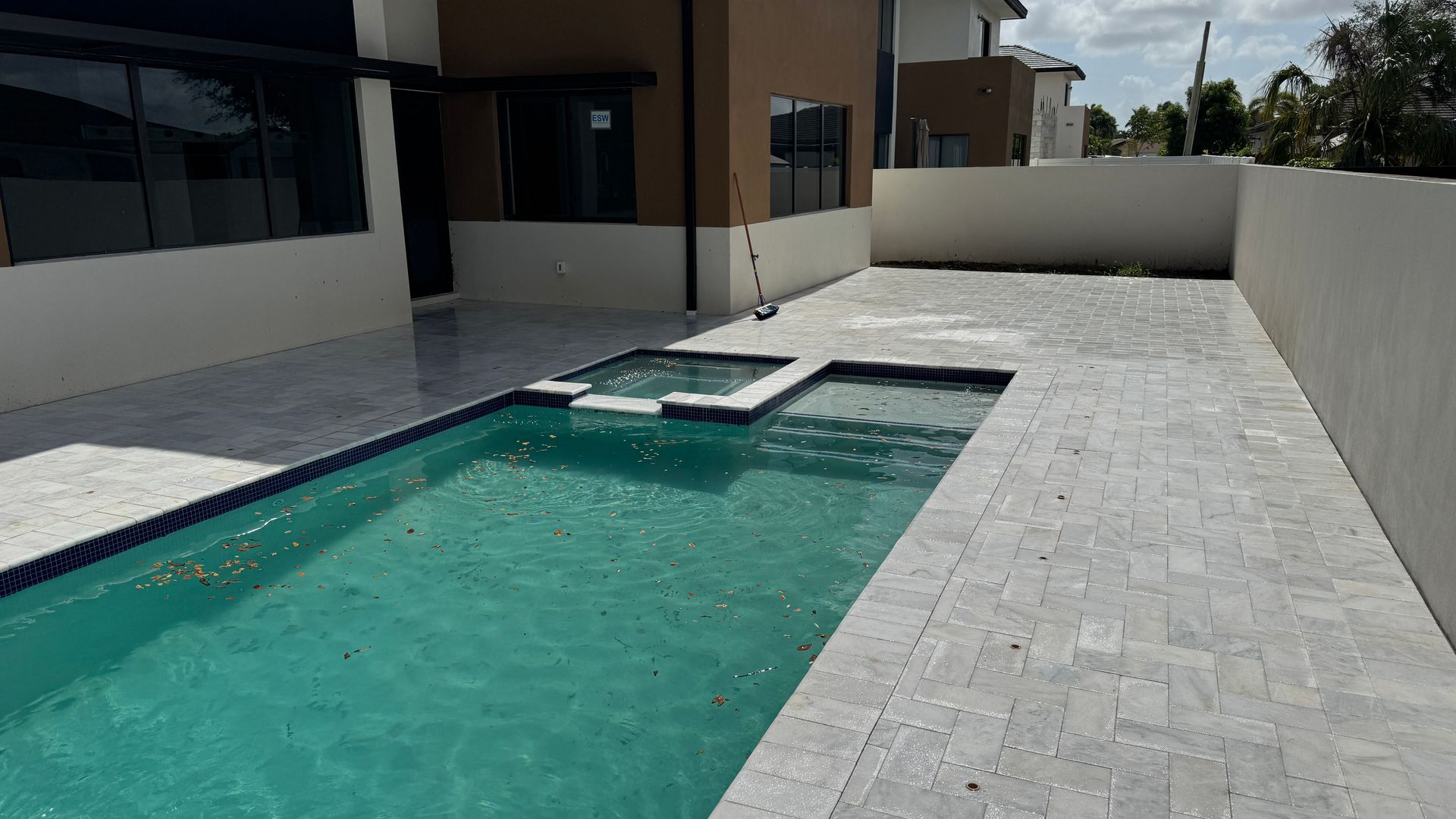 A large swimming pool is in the backyard of a house.