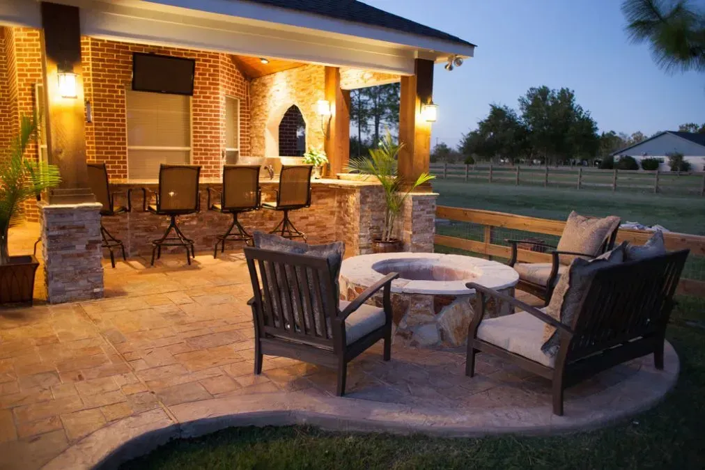 Outdoor patio with fire pit and bar; evening lighting.