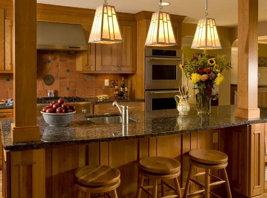 Kitchen with granite countertop, wooden cabinets, and three pendant lights; three bar stools.