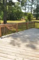 Wooden deck overlooking a sunny park with trees and grass