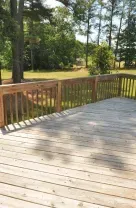 Wooden deck overlooking a sunny park with trees and grass