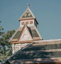 Victorian-style tower with ornate trim and steep roof against a clear blue sky