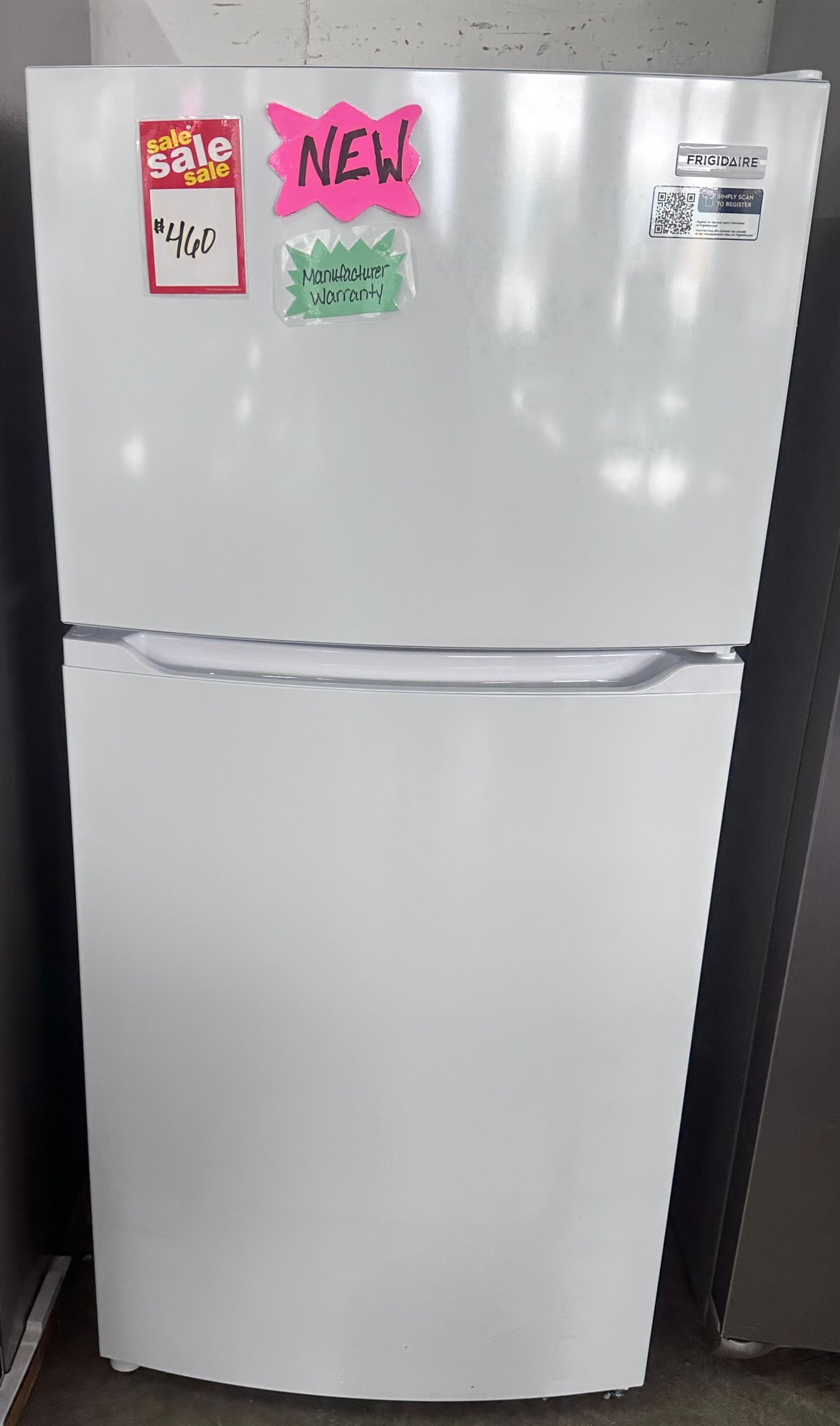 White top-freezer refrigerator with colorful sale stickers on the upper door.