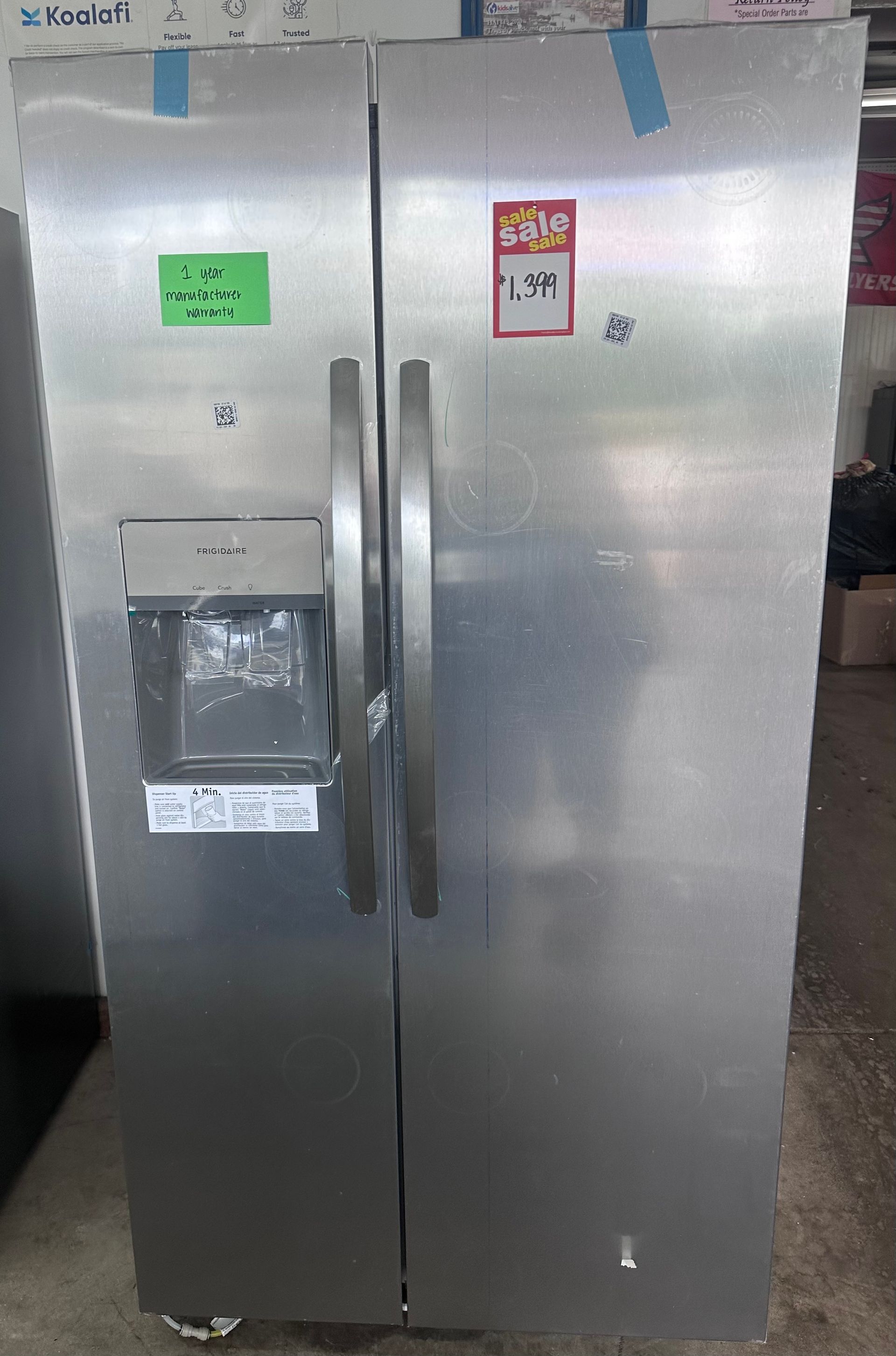Stainless steel side-by-side refrigerator with long vertical handles in a kitchen or store setting