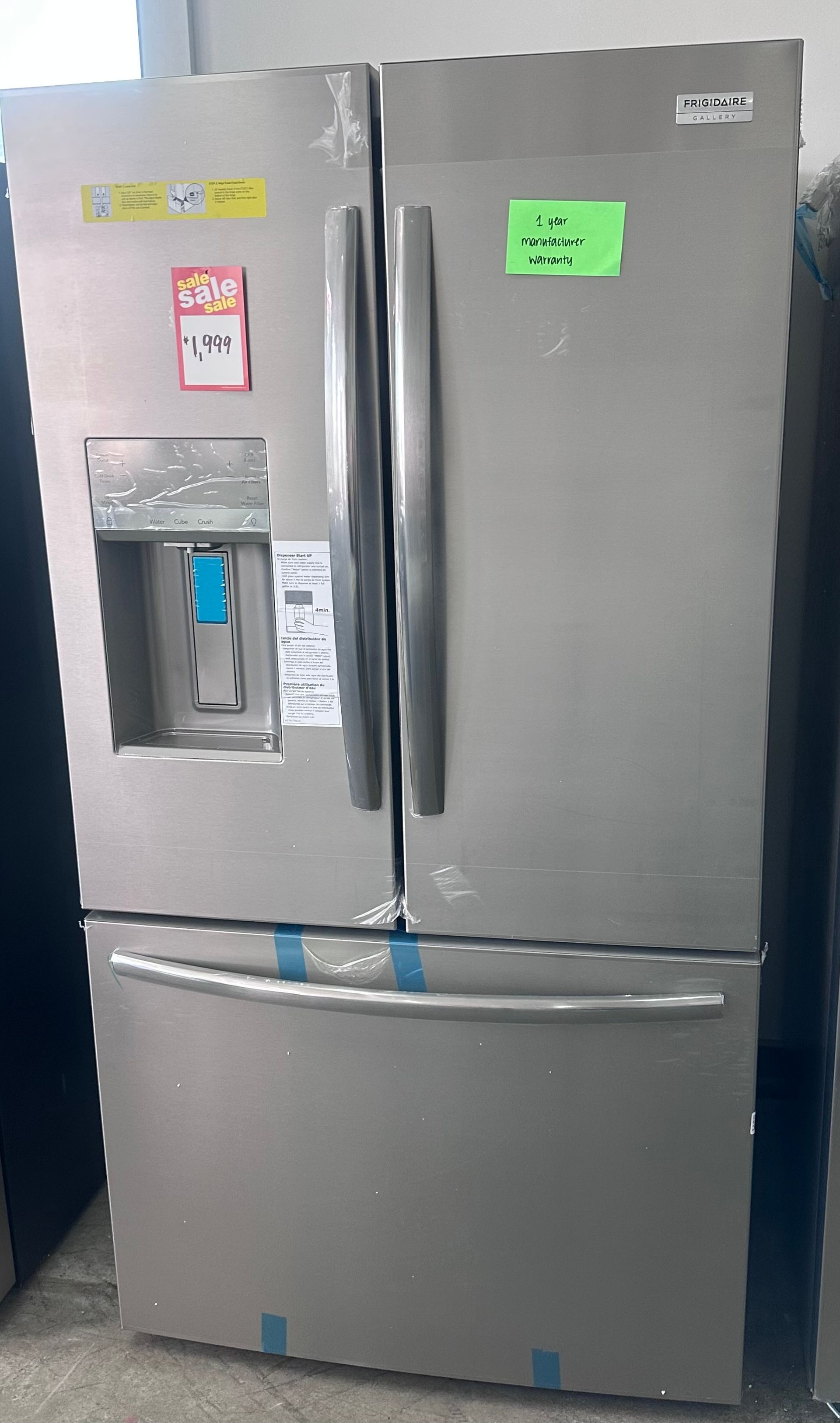 Stainless steel refrigerator with a curved silver door and small stickers near the top.