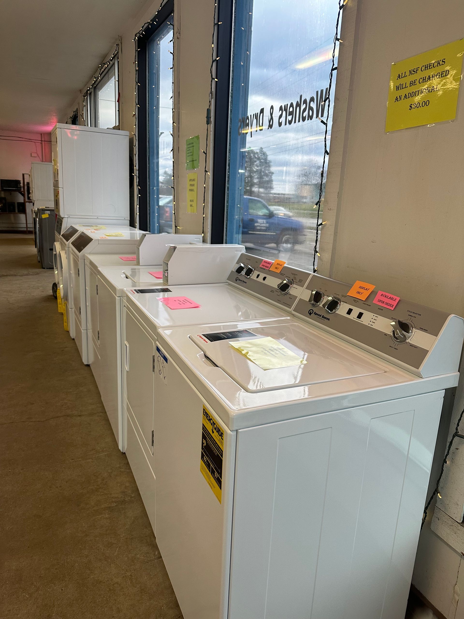 A row of washers and dryers are lined up in a laundromat.